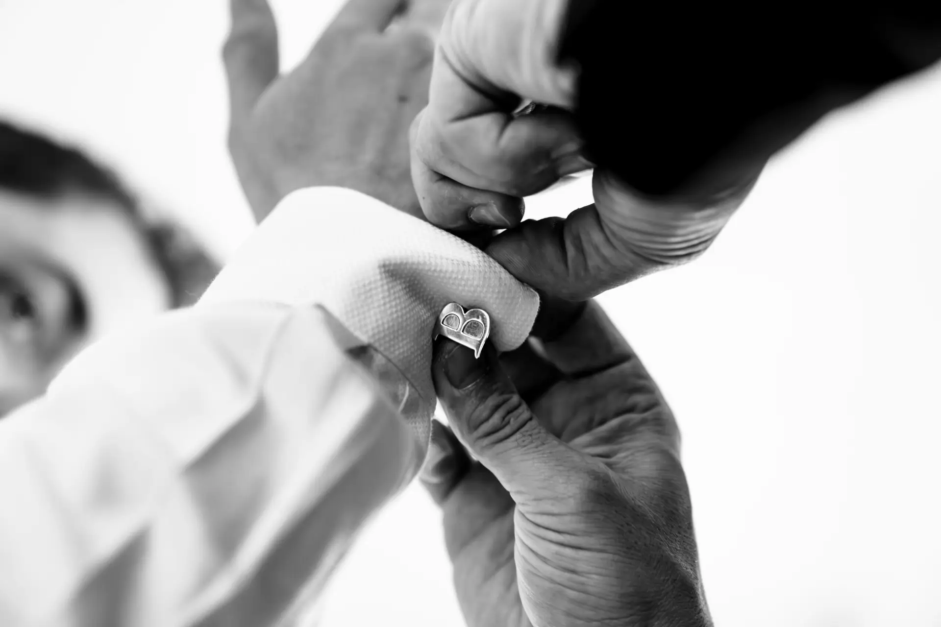Black and white portrait of the groom adjusting his tie before the wedding ceremony